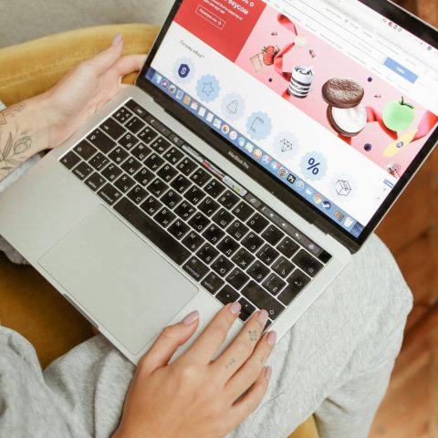 pexels-photo-5585800-5585800 A woman sits comfortably indoors, browsing an online shopping website on her laptop.